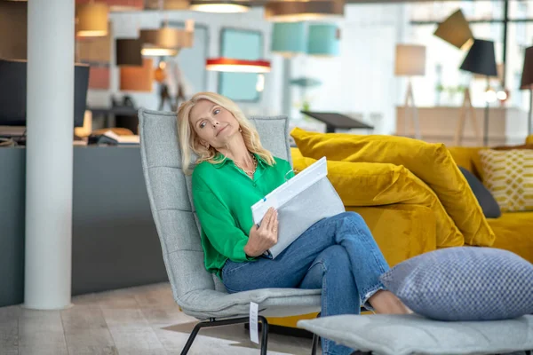 Woman half-lying in a soft chair in a furniture store. — Stock Photo, Image