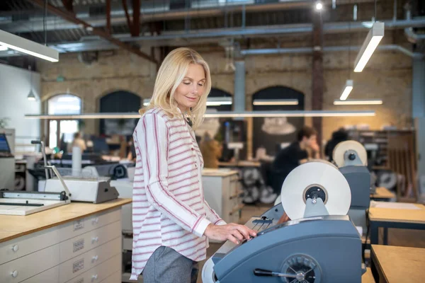 Блондинка регулирует бумажный рулон машины, улыбаясь — стоковое фото