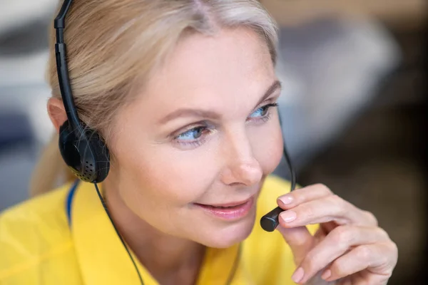 Blonde woman wearing headphones, speaking into microphone — Stock Photo, Image