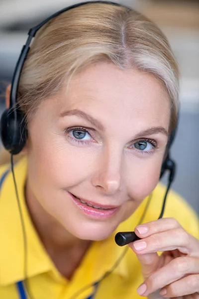 Blonde woman wearing headphones, speaking into microphone, looking into camera — Stock Photo, Image