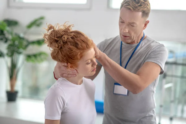 Fisioterapeuta masculino examinando el cuello de una paciente femenina — Foto de Stock
