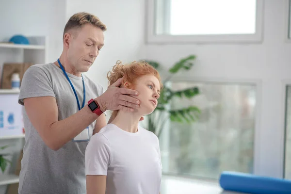 Fisioterapeuta masculino examinando la cabeza del paciente femenino — Foto de Stock