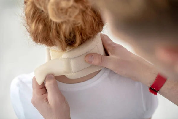 Mannelijke fysiotherapeut handen fixeren nek verband op vrouwelijke patiënt — Stockfoto