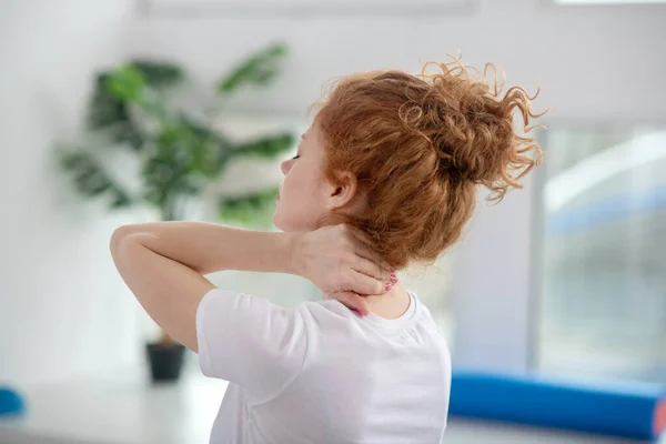 Roodharige vrouwelijke patiënt masseert haar pijnlijke nek — Stockfoto