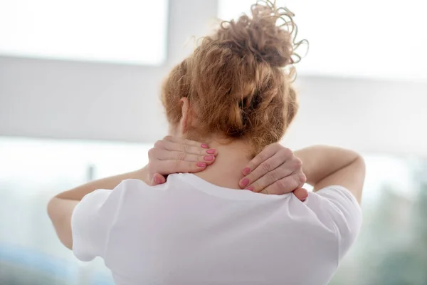 Paciente femenina pelirroja masajeando su doloroso cuello — Foto de Stock