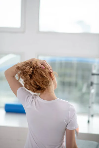 Red-haired female patient stretching her painful neck — Stock Photo, Image