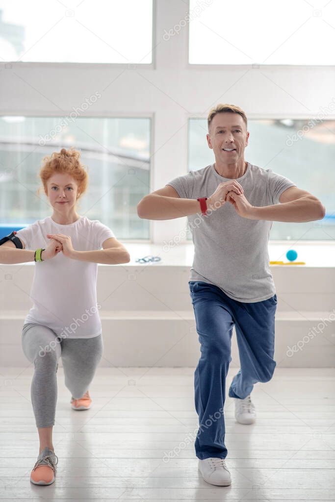 Female patient and male physiotherapist lunging synchronically