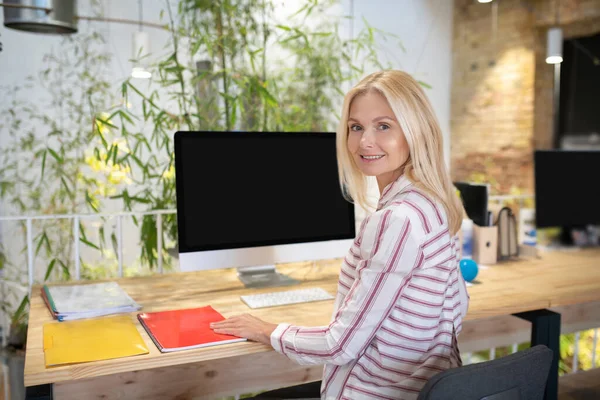 Mujer rubia sentada en el escritorio delante de la pantalla — Foto de Stock
