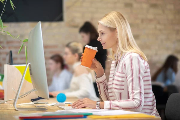 Mujer rubia trabajando en la computadora, bebiendo café —  Fotos de Stock