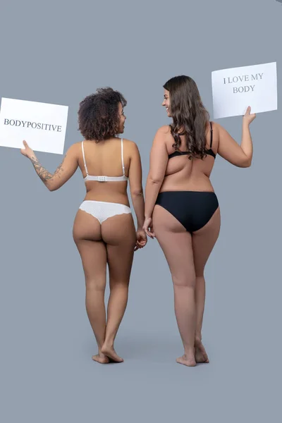 Two women in underwear with posters standing back. — Stock Photo, Image