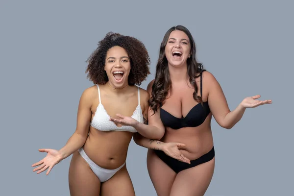 Due ragazze allegre in biancheria intima deliziato diffondere le mani ai lati . — Foto Stock