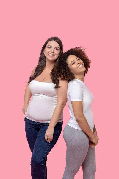 Two young women girlfriends posing on a pink background. — Stock Photo, Image