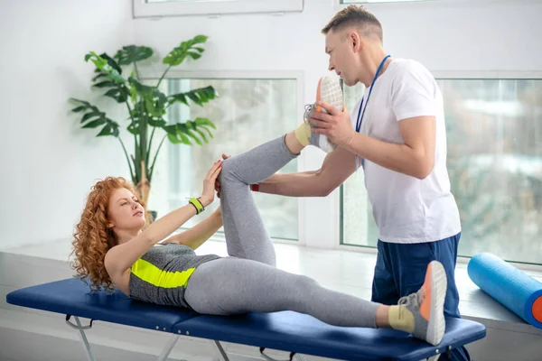 Fisioterapeuta masculino tratando joelho de paciente do sexo feminino — Fotografia de Stock