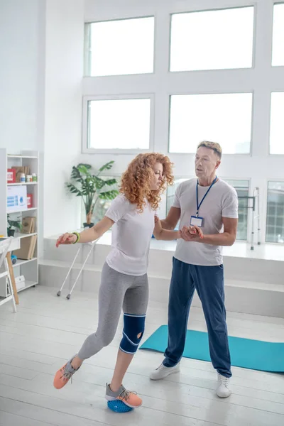 Männlicher Physiotherapeut hilft Patientin das Gleichgewicht zu halten — Stockfoto