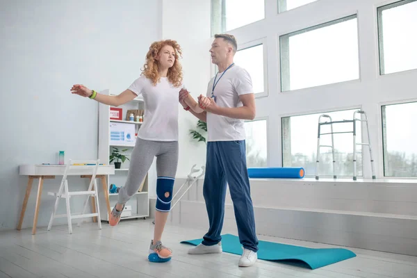 Férfi fizioterapeuta segít a női betegnek egyensúlyban tartani — Stock Fotó