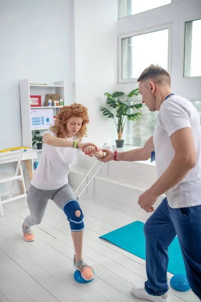 Fisioterapeuta masculino apoiando paciente do sexo feminino com lunging — Fotografia de Stock