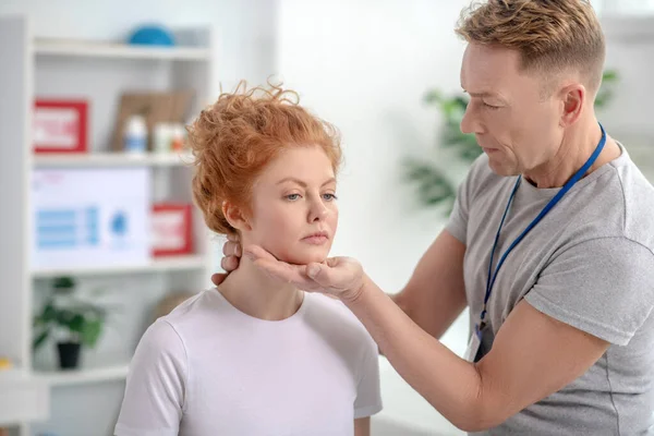 Fisioterapeuta masculino examinando el cuello de una paciente femenina — Foto de Stock