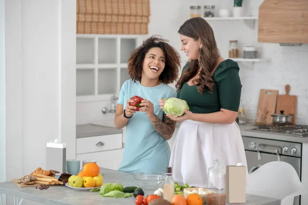 Две молодые женщины с овощами стоят на кухне . — стоковое фото
