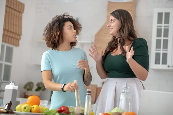 Две девушки разговаривают во время приготовления вегетарианского блюда . — стоковое фото
