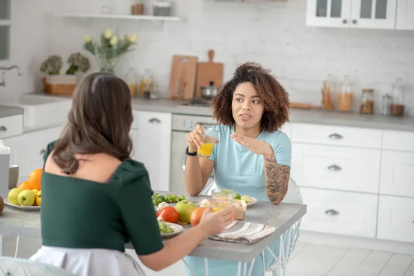 Две женщины завтракают, разговаривают на кухне дома . — стоковое фото
