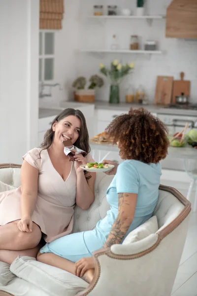 Two girlfriends sitting on a small cozy sofa at home. — Stock Photo, Image