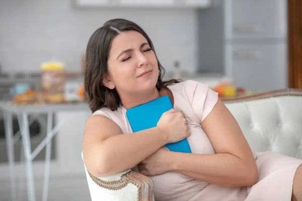 Donna dai capelli scuri con gli occhi chiusi che abbraccia una tavoletta blu . — Foto Stock