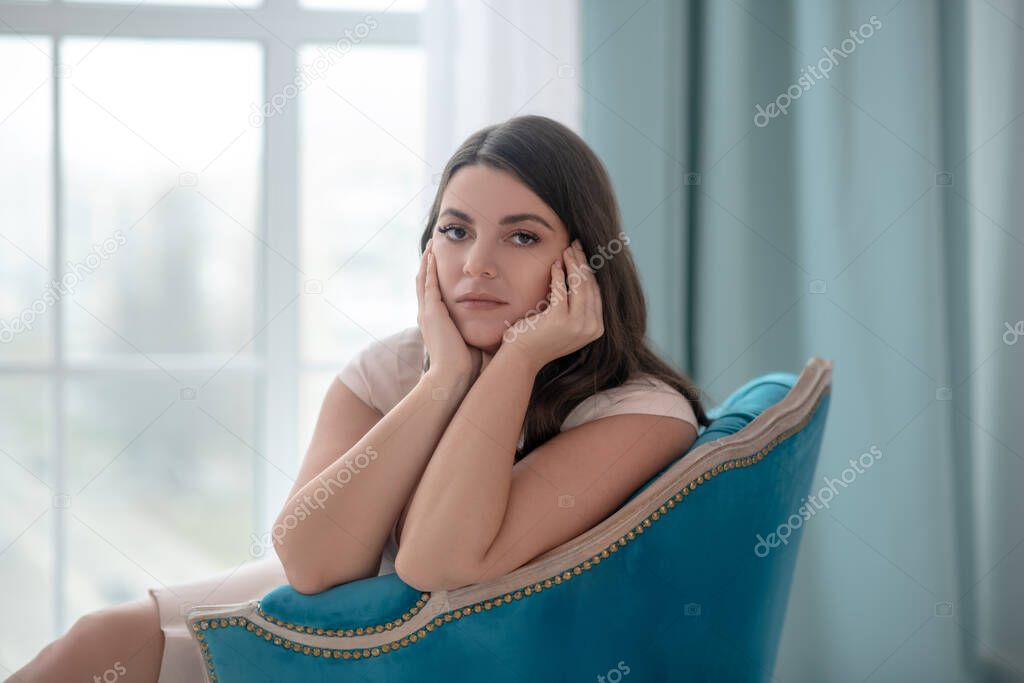 Young woman with a european appearance sitting in a armchair.