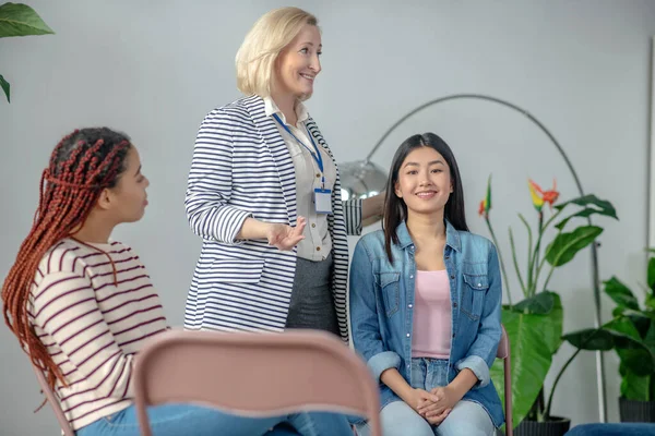 Psicólogo loira em uma blusa de rosa falando com mulheres jovens — Fotografia de Stock