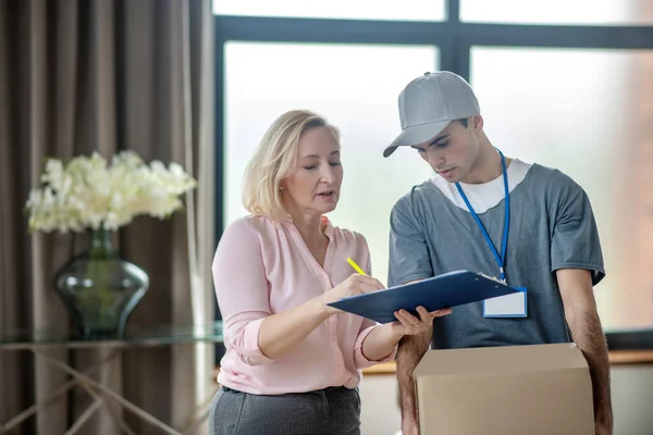 Blondine vrouw in een roze blouse voldoen aan de bevalling courrier — Stockfoto