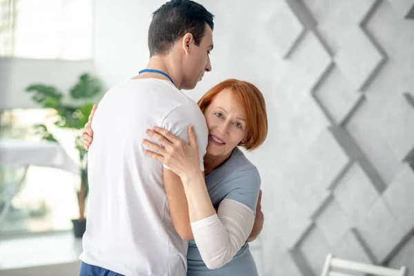 Positive grateful aged patient hugging her therapist — Stock Photo, Image