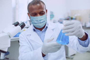 Tıbbi maske takan profesyonel bir laboratuvar çalışanı.