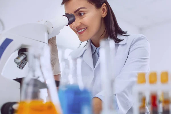 Virologista feminina positiva olhando para o microscópio — Fotografia de Stock