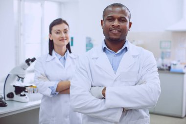 Neşeli biyologlar laboratuarda yan yana duruyorlar.