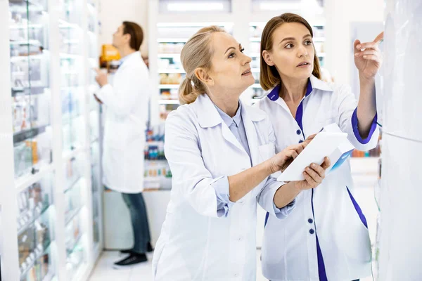 Farmacêuticos femininos Pensivos em casacos brancos contando medicina — Fotografia de Stock