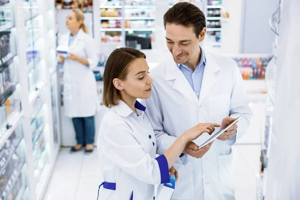 Dois farmacêuticos verificando a disponibilidade de medicamentos em uma farmácia . — Fotografia de Stock