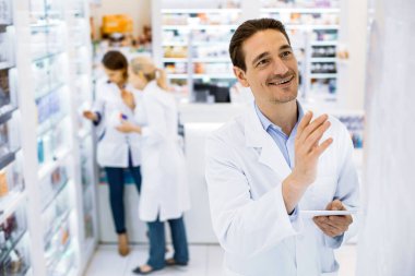 Eczanede tabletle gülümseyen erkek eczacı..