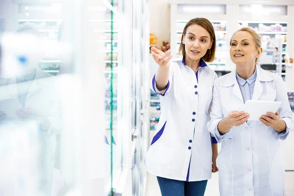 Duas farmacêuticas estudando uma vitrine em uma farmácia — Fotografia de Stock