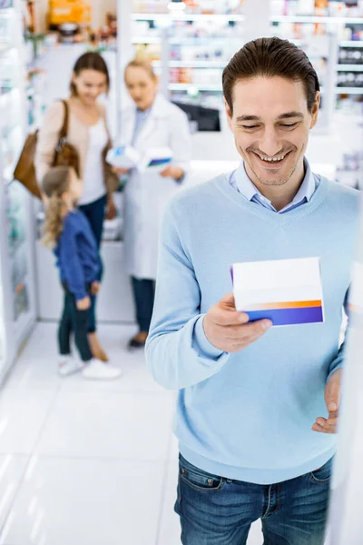 Homem feliz alegre examinando pílulas em uma farmácia — Fotografia de Stock