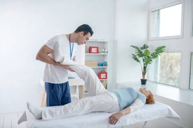 Profesyonel terapist hastalarının bacağını kaldırıyor.