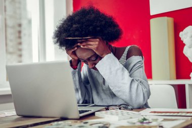 Yorgun Afrikalı Amerikalı kadın alnına dokunuyor.