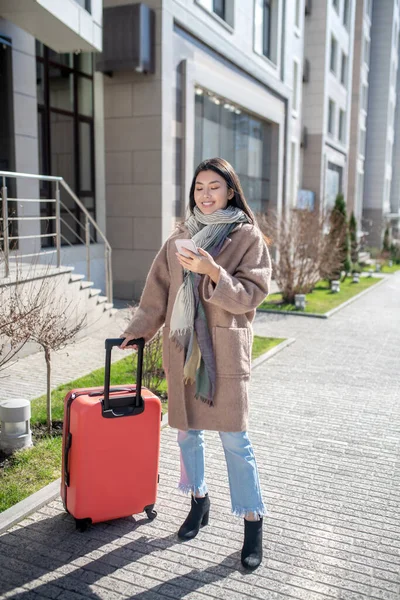 Mladý asijský žena v béžový kabát stojící v blízkosti budovy — Stock fotografie