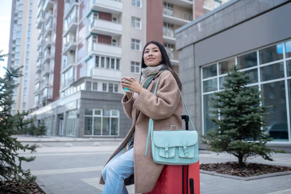 Mujer joven de cabello oscuro con un abrigo beige tomando café —  Fotos de Stock