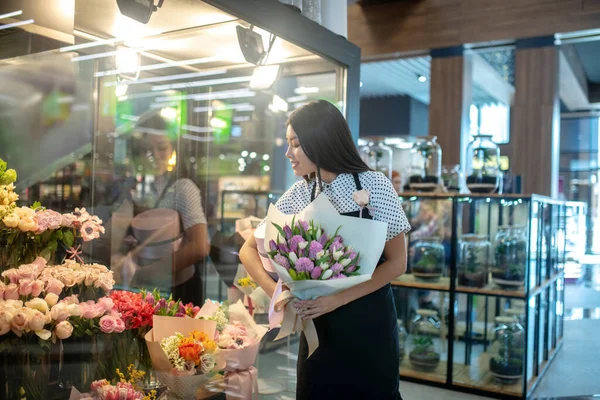 Dark-haired asian flower shop assistant workling in a shop