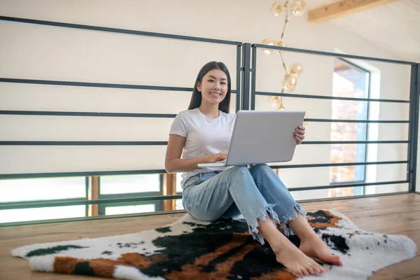 Fiatal nő ül a tetején leszállás, kezében laptop térden, gépelés — Stock Fotó