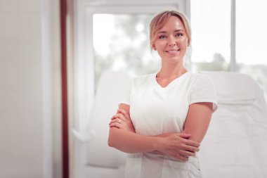 Başarılı bir yetişkin dermatolog güzellik salonunda duruyor.