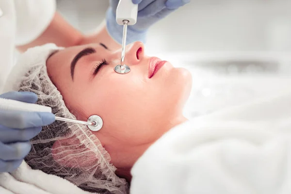 Cosmetologista usando luvas fazendo aparato de limpeza facial para a mulher — Fotografia de Stock