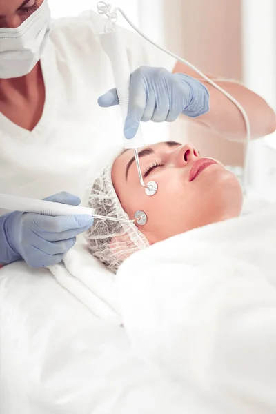 Cosmetólogo vistiendo uniforme blanco haciendo limpieza facial para mujer —  Fotos de Stock