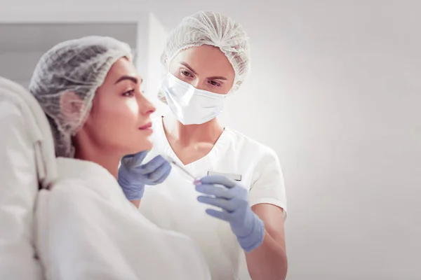 Dark-eyed female cosmetologist providing mesotherapy for woman — Stock Photo, Image