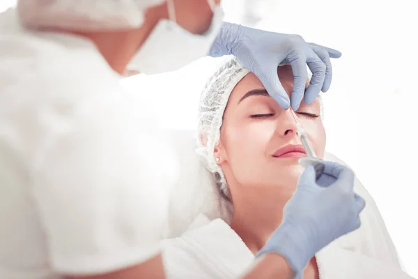 Cosmetologist doing beauty shot into upper part of nose — Stock Photo, Image