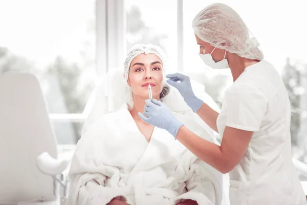 Cosmetólogo usando guantes azules haciendo belleza disparado en el labio — Foto de Stock